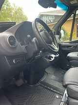 Driver's seat view of an RV rental van interior, showing the Mercedes-Benz steering wheel and dashboard.