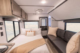 Explore this modern RV rental interior with a comfy bed, sofa, windows with views, and practical overhead storage.