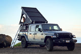 Jeep Gladiator with rooftop tent for an RV rental. A person in the tent enjoys ocean views from this ultimate overlanding setup.