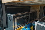 Organized RV rental utility bay with custom-built storage, power outlets, and an open drawer for tools.