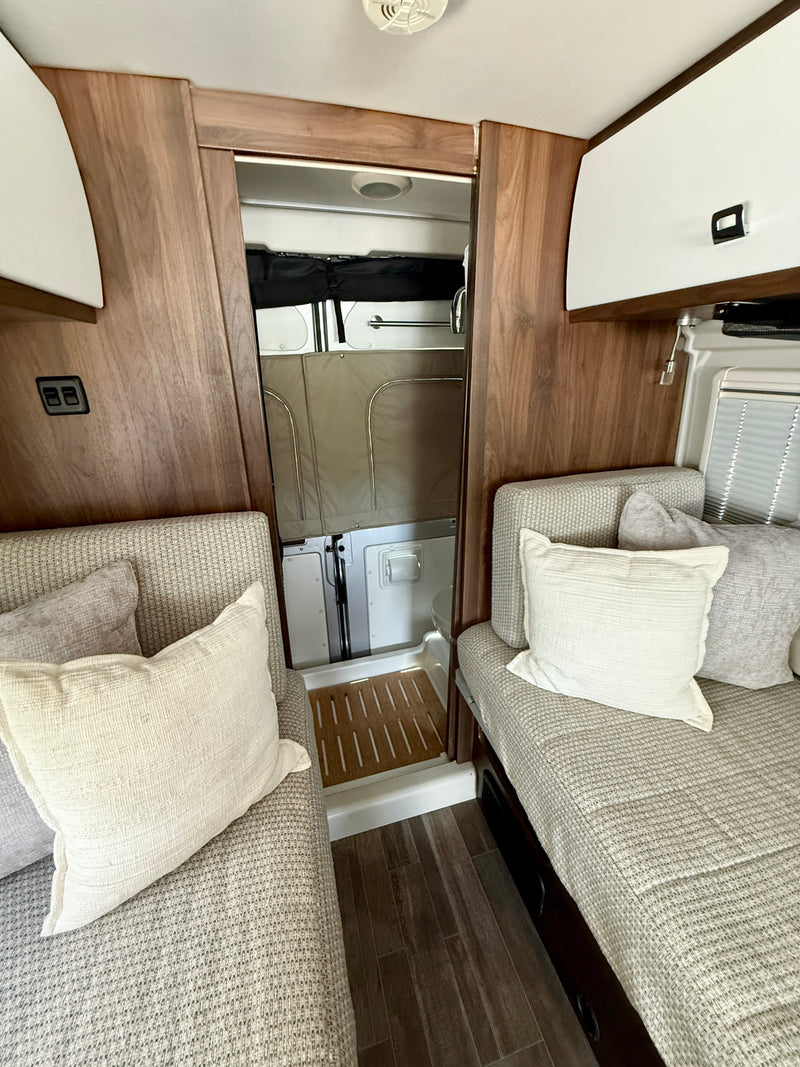 RV rental interior: two cozy bench seats, wood accents, and a compact shower. Bright and modern living space. — photo 16