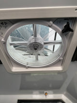 Low-angle view of an RV rental ceiling fan. Mesh screen, blades, and control knob visible for ventilation.