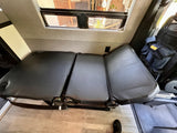 RV rental interior featuring a versatile three-section convertible bench seat with window view and power outlet.