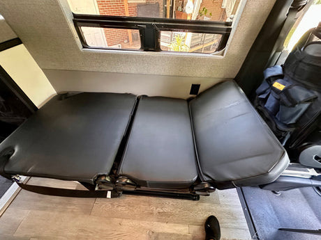RV rental interior featuring a versatile three-section convertible bench seat with window view and power outlet.