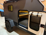 Compact teardrop RV rental with an open door, revealing bunk beds inside. Perfect for adventure trips.