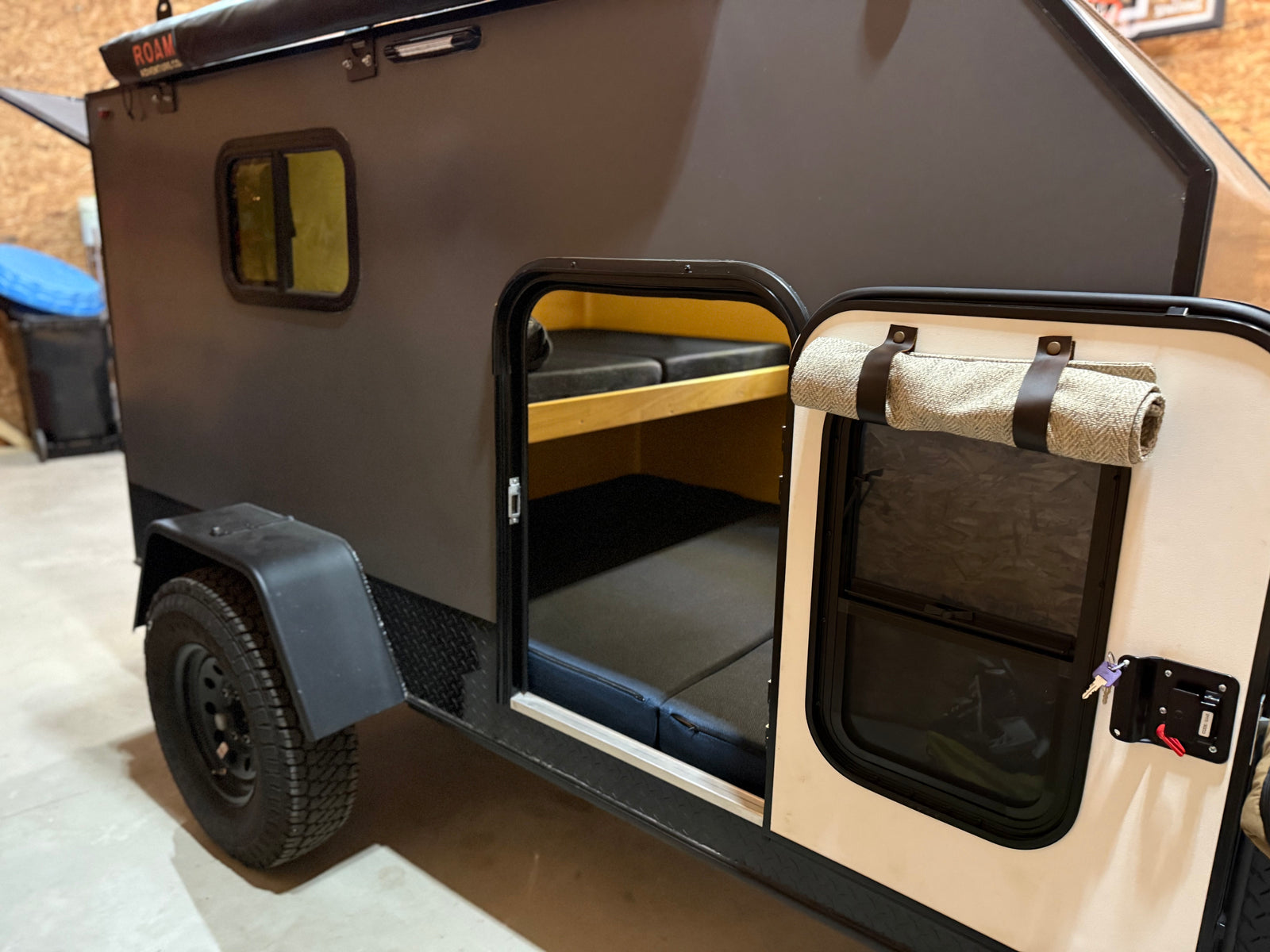 Compact teardrop RV rental with an open door, revealing bunk beds inside. Perfect for adventure trips.