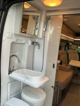 This RV rental's compact wet bath features a folding sink, toilet, shower, and mirror for convenient travel.