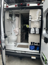 Explore this rv rental's interior. A camper van's rear shows a wet bath (toilet, shower) & storage with a Thule ladder.