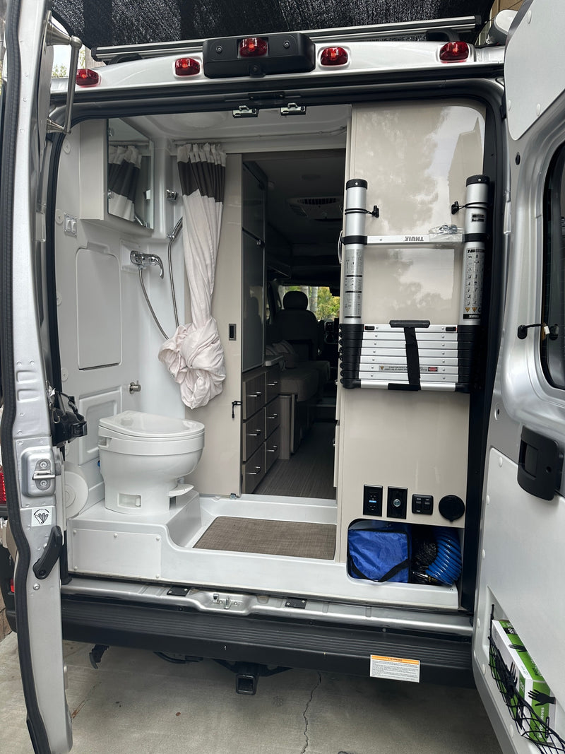 Explore this rv rental's interior. A camper van's rear shows a wet bath (toilet, shower) & storage with a Thule ladder. — photo 18