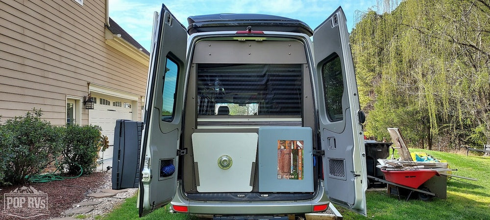 This RV camper van with open doors shows interior storage, ready for your next rv rental adventure!