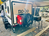 Compact no bo rv rental setup: rear of travel trailer with gear at a campsite, perfect for outdoor adventures.
