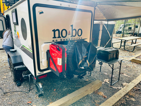 Compact no bo rv rental setup: rear of travel trailer with gear at a campsite, perfect for outdoor adventures.