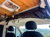 Cozy RV rental interior: wooden ceiling, roof vent, dreamcatcher, and mountain views from the front seats.
