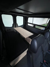 This RV rental features a functional interior with a light wood table, black padded benches, and large windows.