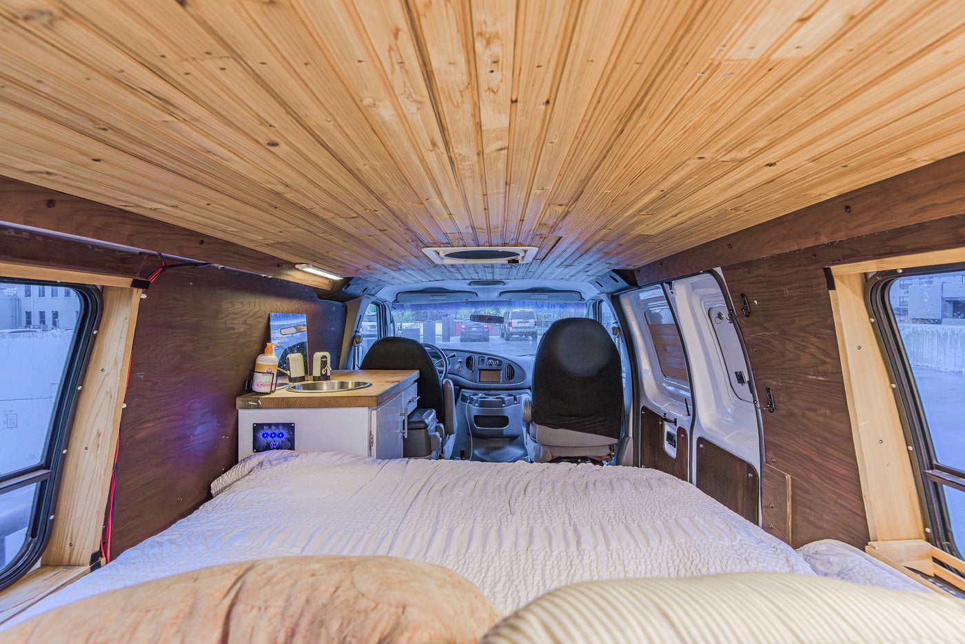  parked on a wet deck overlooking city buildings and mountains.|Cozy RV rental interior featuring a comfortable bed — photo 7