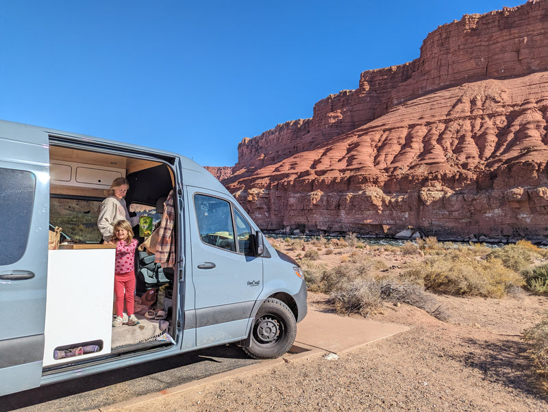 An RV rental camper van adventure: family enjoying their van parked by a desert river and majestic red cliffs. — photo 9