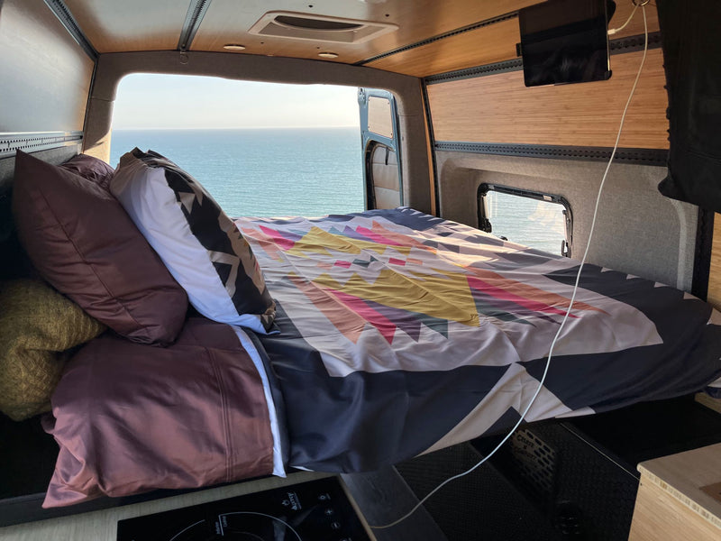 This RV rental offers a comfy bed with an epic ocean view from the van's open rear. Perfect for mobile adventures. — photo 3