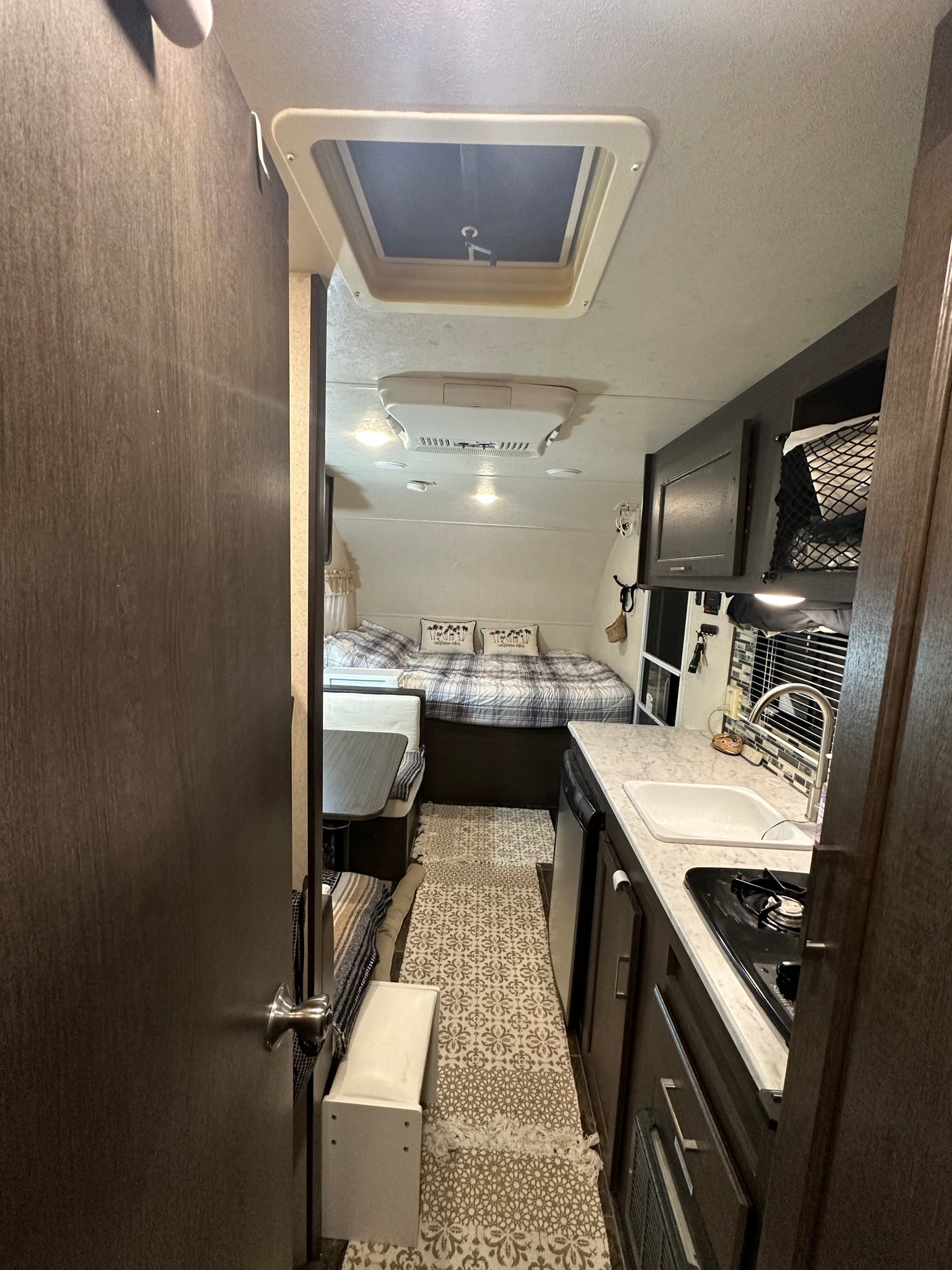 Cozy RV rental interior with a compact kitchen, bed, and dinette area.