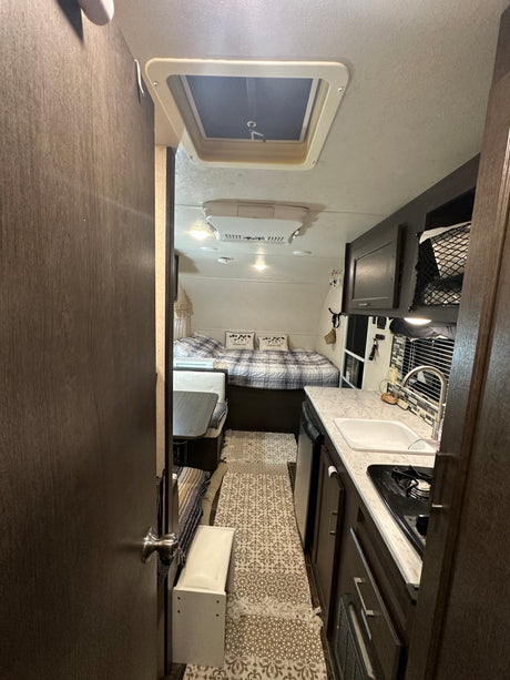 Cozy RV rental interior with a compact kitchen, bed, and dinette area.