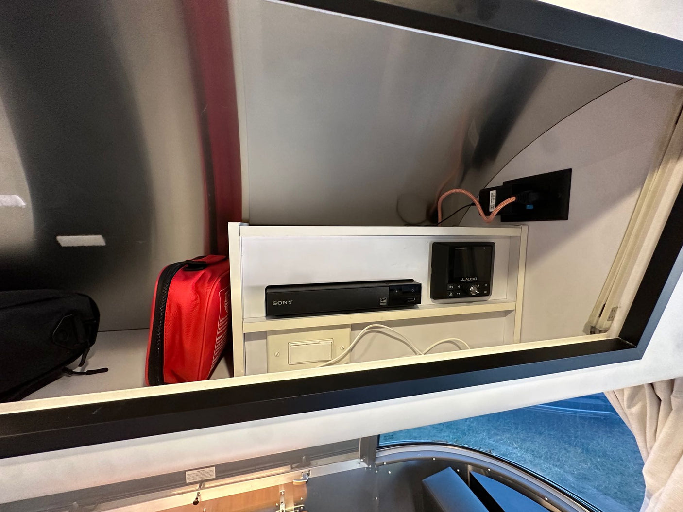 RV rental interior: overhead storage with Sony media player, JL Audio stereo, and a red first aid kit.