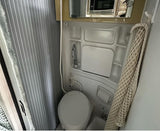 Compact RV rental wet bath with toilet, sink/shower, and hanging towel.