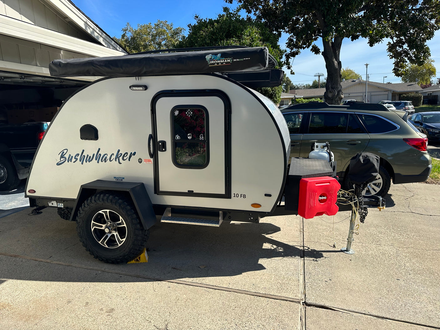 A compact "Bushwhacker" teardrop RV, equipped with an Ironman awning and RotopaX, ideal for an RV rental adventure.