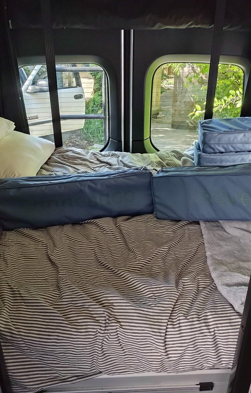 Revel RV rental interior: striped bed, pillow, and Omnesdo storage bags for a comfy journey. — photo 6