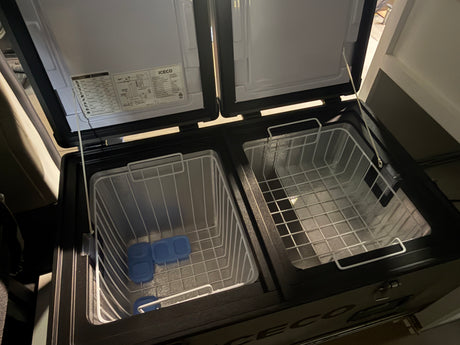 Open dual-zone portable fridge/freezer with wire baskets and ice packs, ideal for your RV rental or camping adventure.