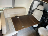 Inside an RV rental: Cream leatherette bench and swiveled front seats with a dark wood foldable table. Perfect for your travels.
