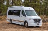 A white Mercedes-Benz Sprinter RV rental is parked on a dirt road amidst green pine trees, ready for your next trip.