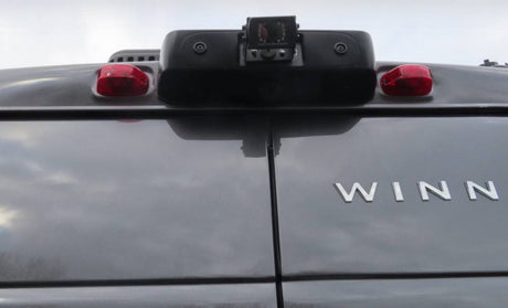 RV rental's rear: dark gray body, central backup camera, red lights, and 'WINN' logo.