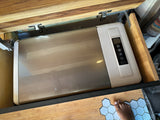 RV rental: Portable fridge with control panel nestled in a custom camper cabinet. Foot on hexagonal floor.