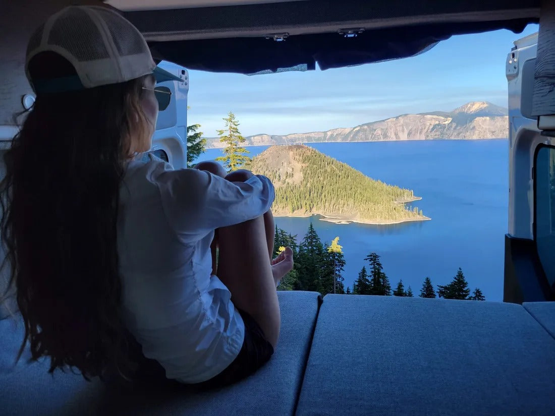 Serene lake view from an RV rental! A person in a van enjoys the breathtaking Crater Lake, perfect for van life travel.