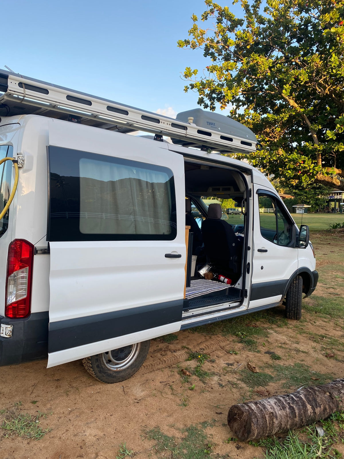 White Ford Transit RV rental van, with open side door revealing a cozy interior. — photo 20