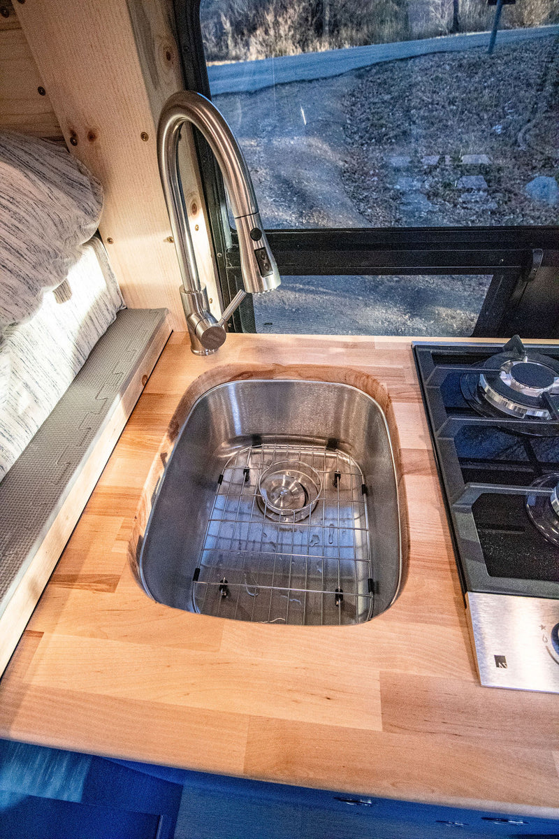  & driver's area. Parked by river.|Vibrant blue interior of this RV rental camper van boasts a raised bed — photo 2