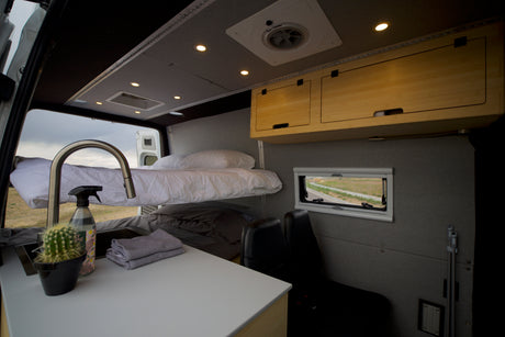 Comfortable RV rental interior: bunk beds, kitchen, and overhead storage for your next adventure.