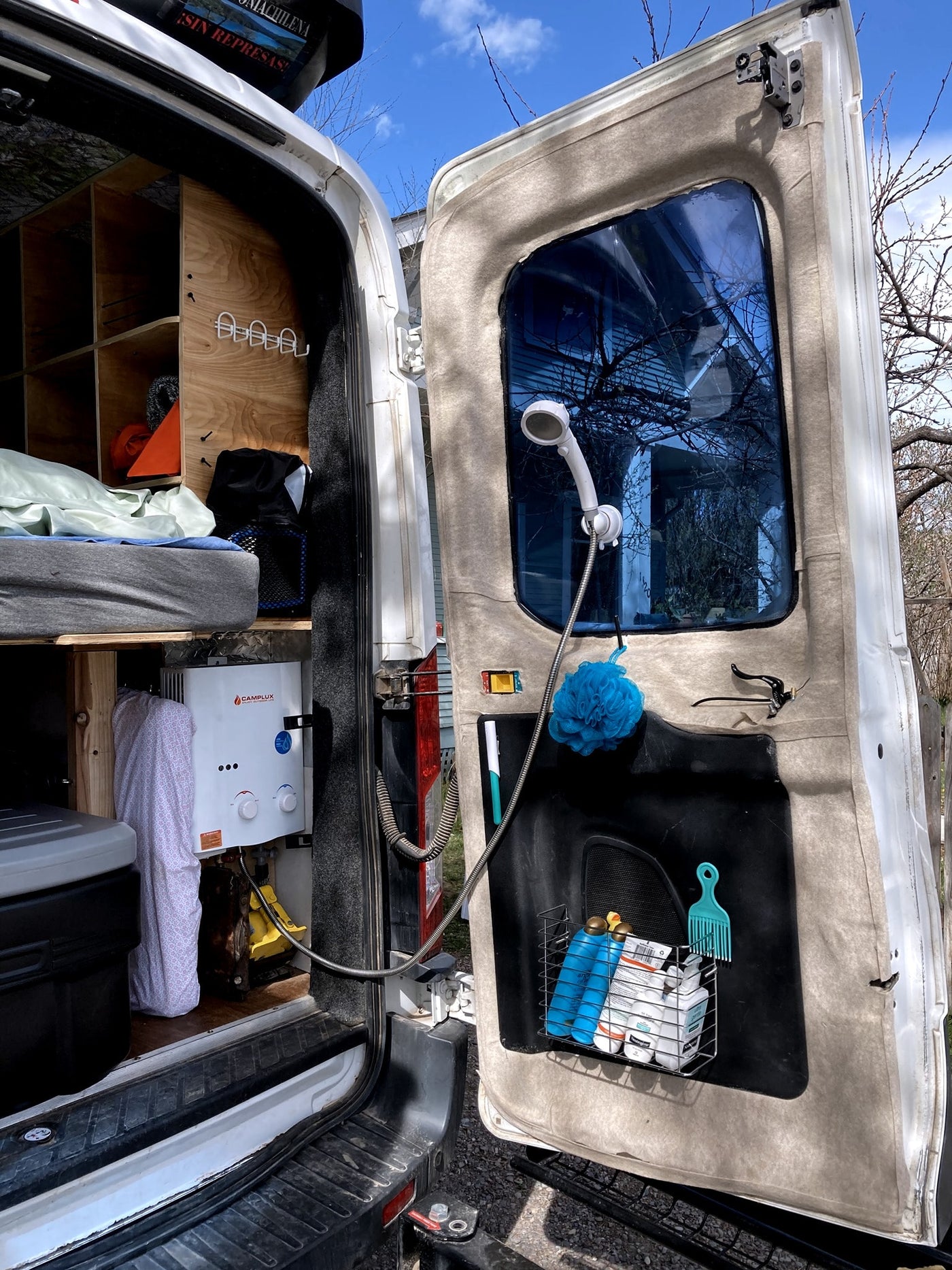RV rental features: an outdoor shower from the back of the van, with a water heater, shower head, and toiletries visible. — photo 6