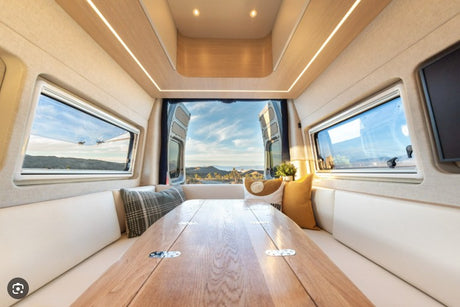 Relax in this modern RV rental interior, featuring a spacious dining area, cozy seating, and stunning scenic views out the back.