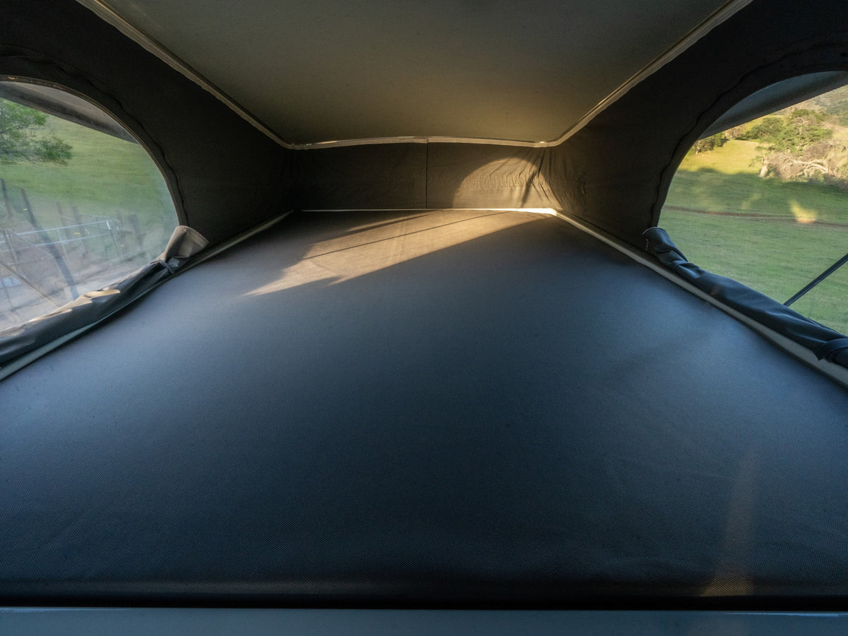 Experience an RV rental! Inside a pop-top camper's sleeping area with windows revealing sunny green outdoor views. — photo 18