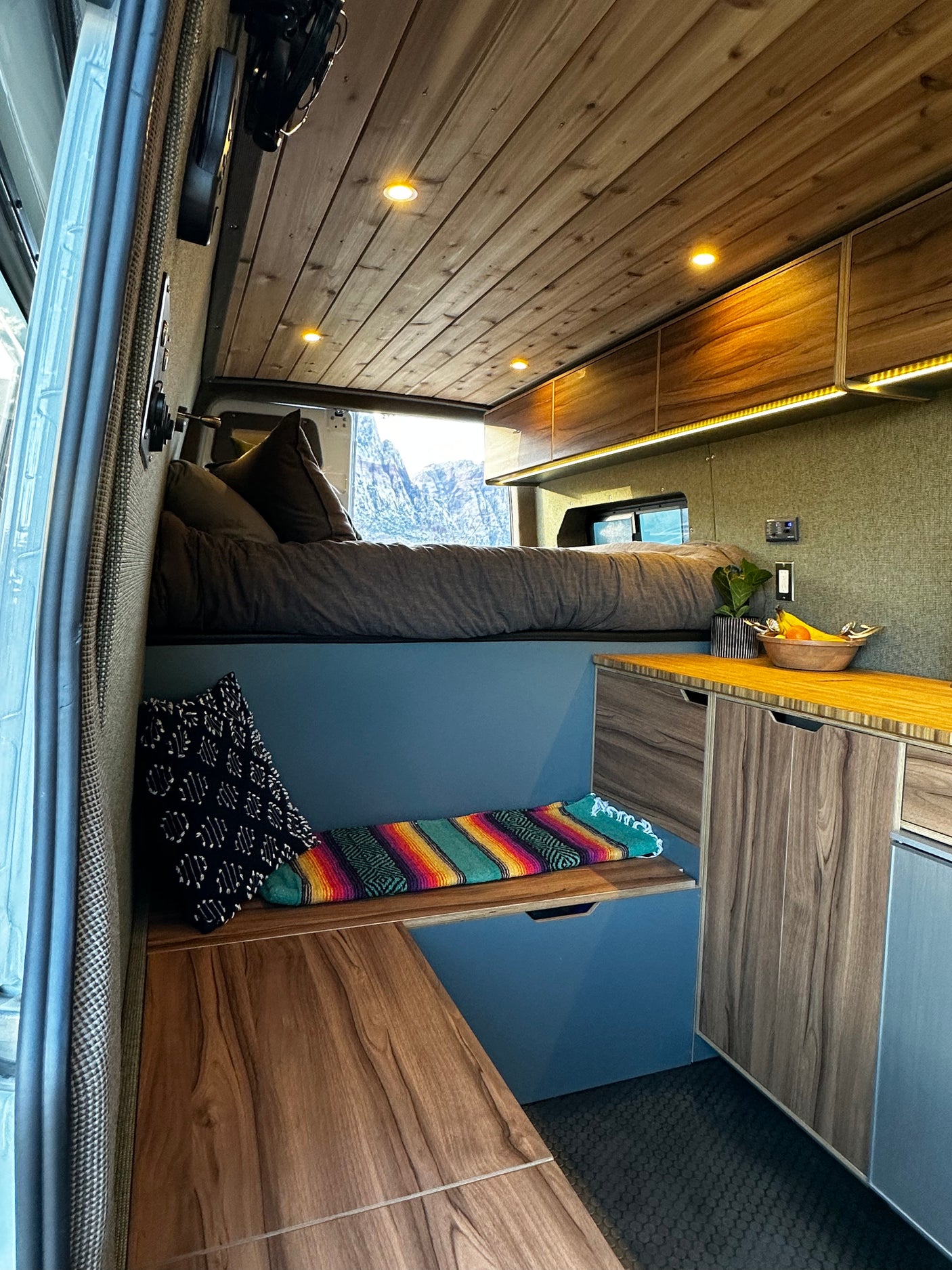 Cozy camper van interior, ideal for RV rental adventures, with a comfortable bed, kitchenette, and mountain views.