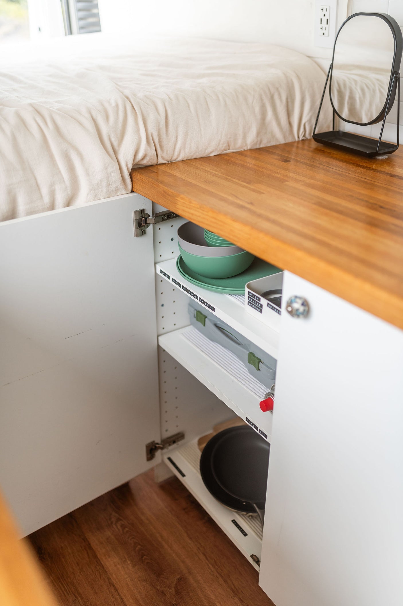 Organized kitchen storage in an RV rental, with neatly labeled shelves holding dishes, cookware, and essentials.