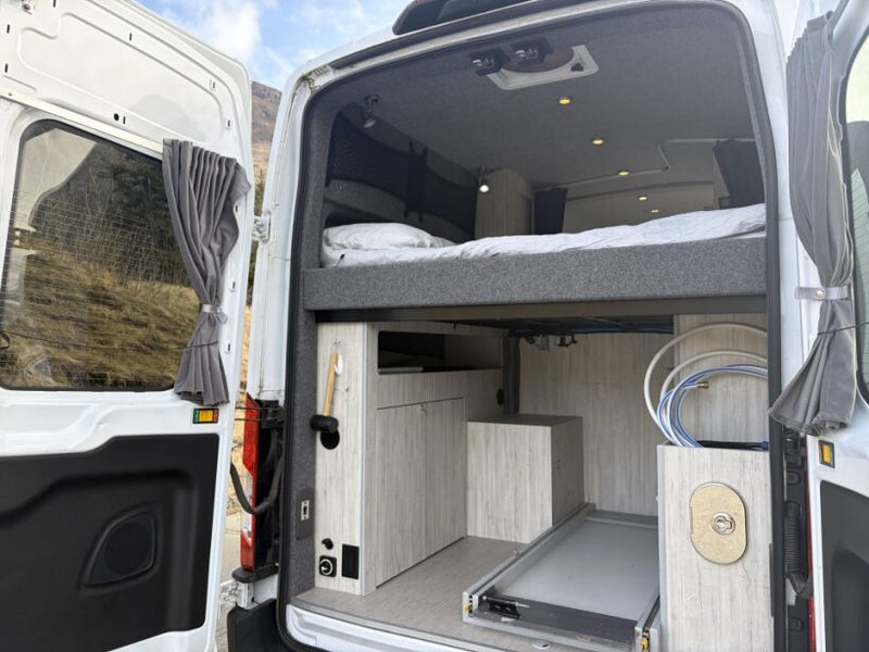  and comfortable seating.|This RV rental offers a cozy camper van bed facing the rear window — photo 4