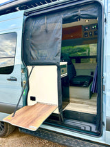 This camper van RV rental features an open side door with a mesh screen, fold-out table, and a peek inside.
