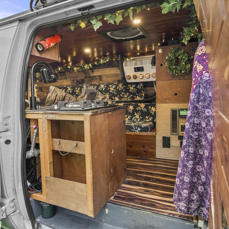 Inside this RV rental, a compact kitchen with stove, cozy seating, and wooden decor creates a homey mobile space.