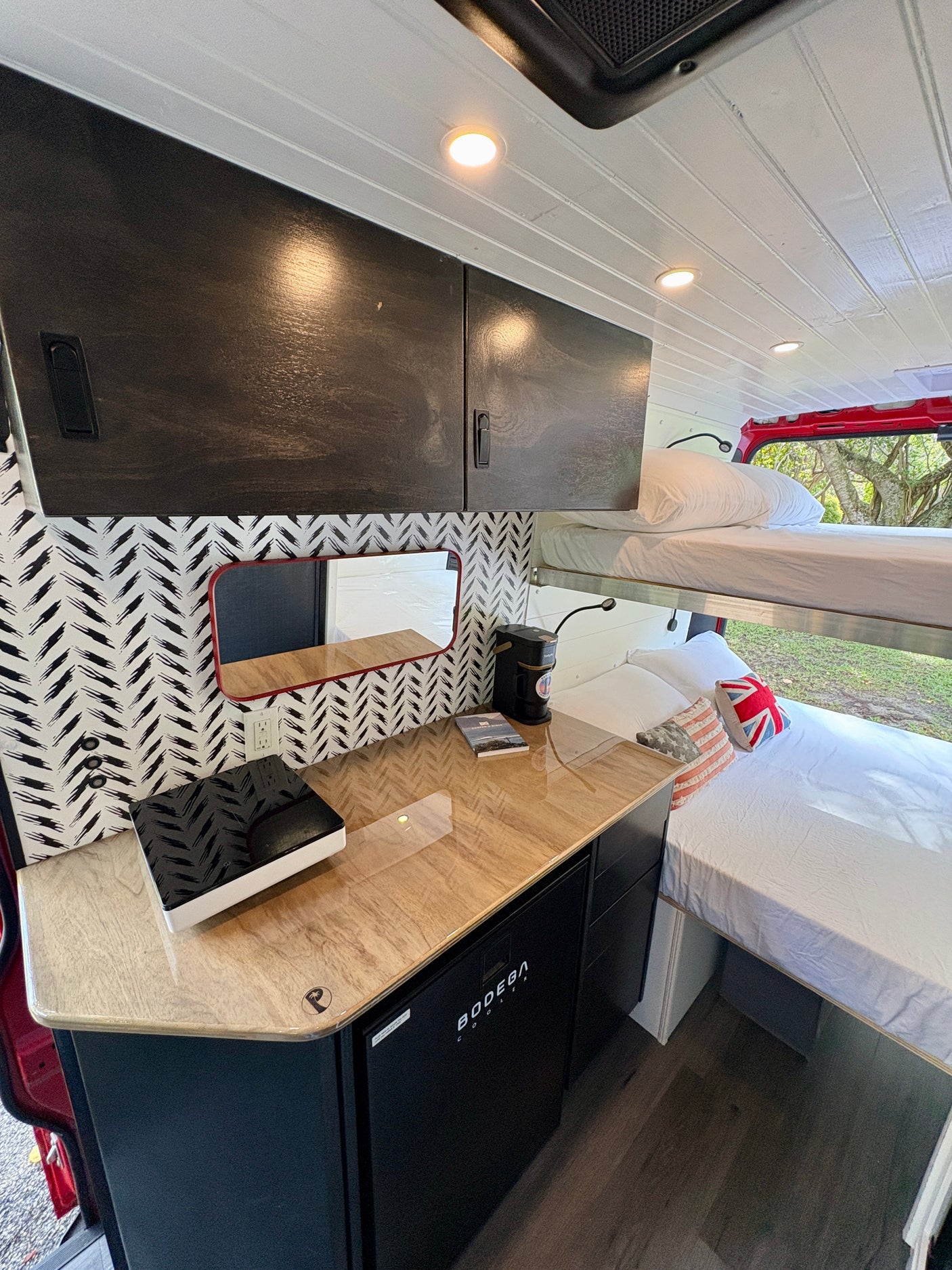 Modern rv rental interior with bunk beds, a kitchenette, fridge, and stylish storage solutions for your journey.