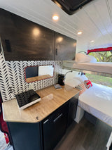 Modern rv rental interior with bunk beds, a kitchenette, fridge, and stylish storage solutions for your journey.