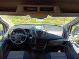 View of an RV rental's Ford Transit van interior, featuring the dashboard, steering wheel, and front seats.