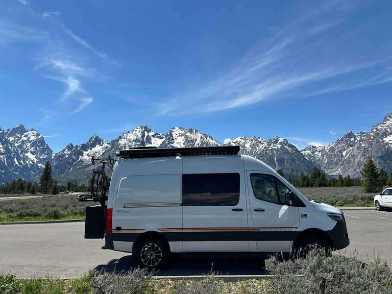  snow-capped Grand Teton mountains under a blue sky.|Modern RV rental van parked lakeside — photo 10