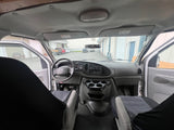 Interior of a Ford **RV rental** van, looking forward. Features include the dashboard, steering wheel, front seats, and the exterior through the windshield.
