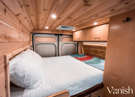 This cozy rv rental interior features a full bed, warm wooden walls & ceiling, and smart storage, perfect for your next adventure.